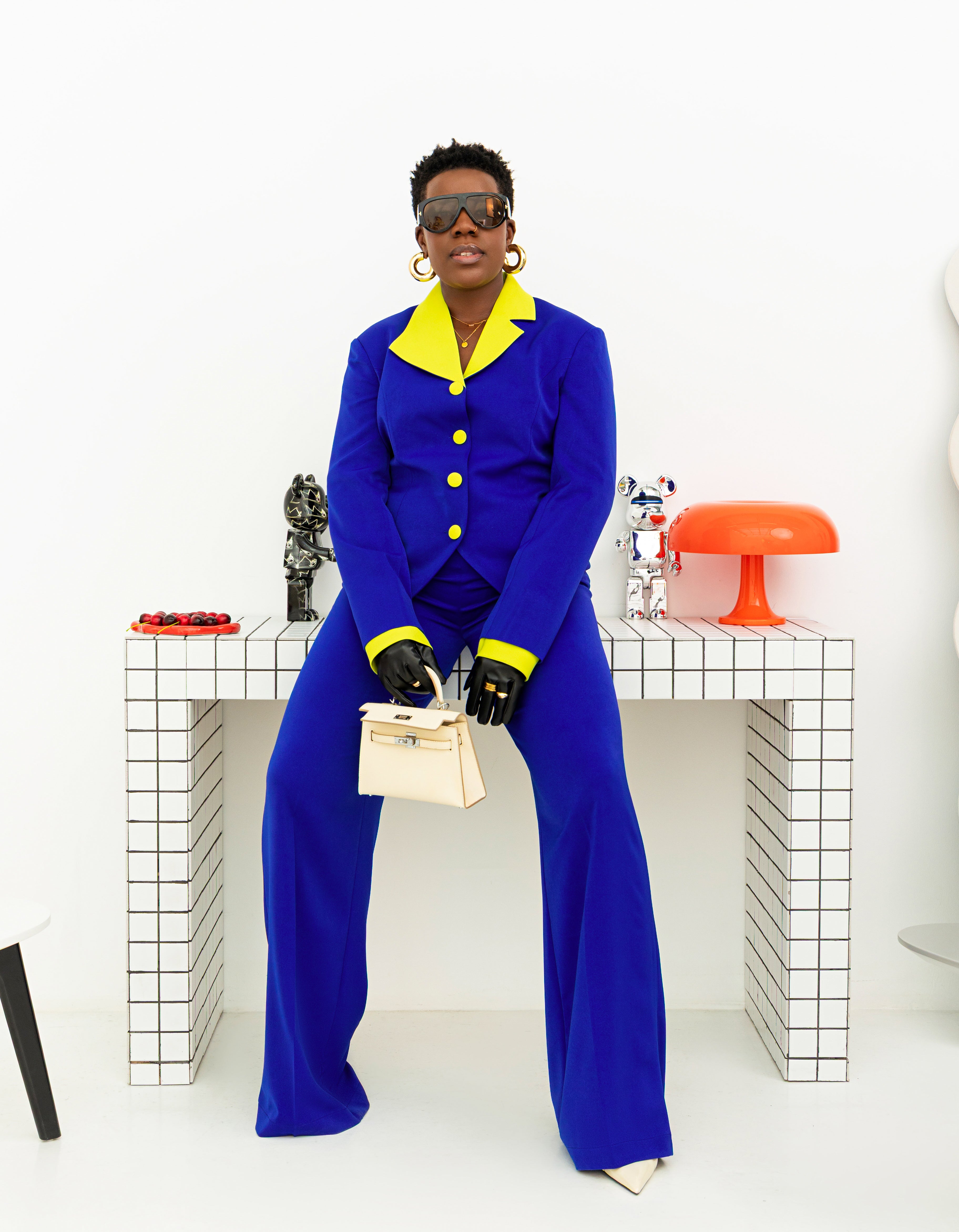 Contemporary royal blue pantsuit with neon details, worn by a model posing on a checkered and white background.