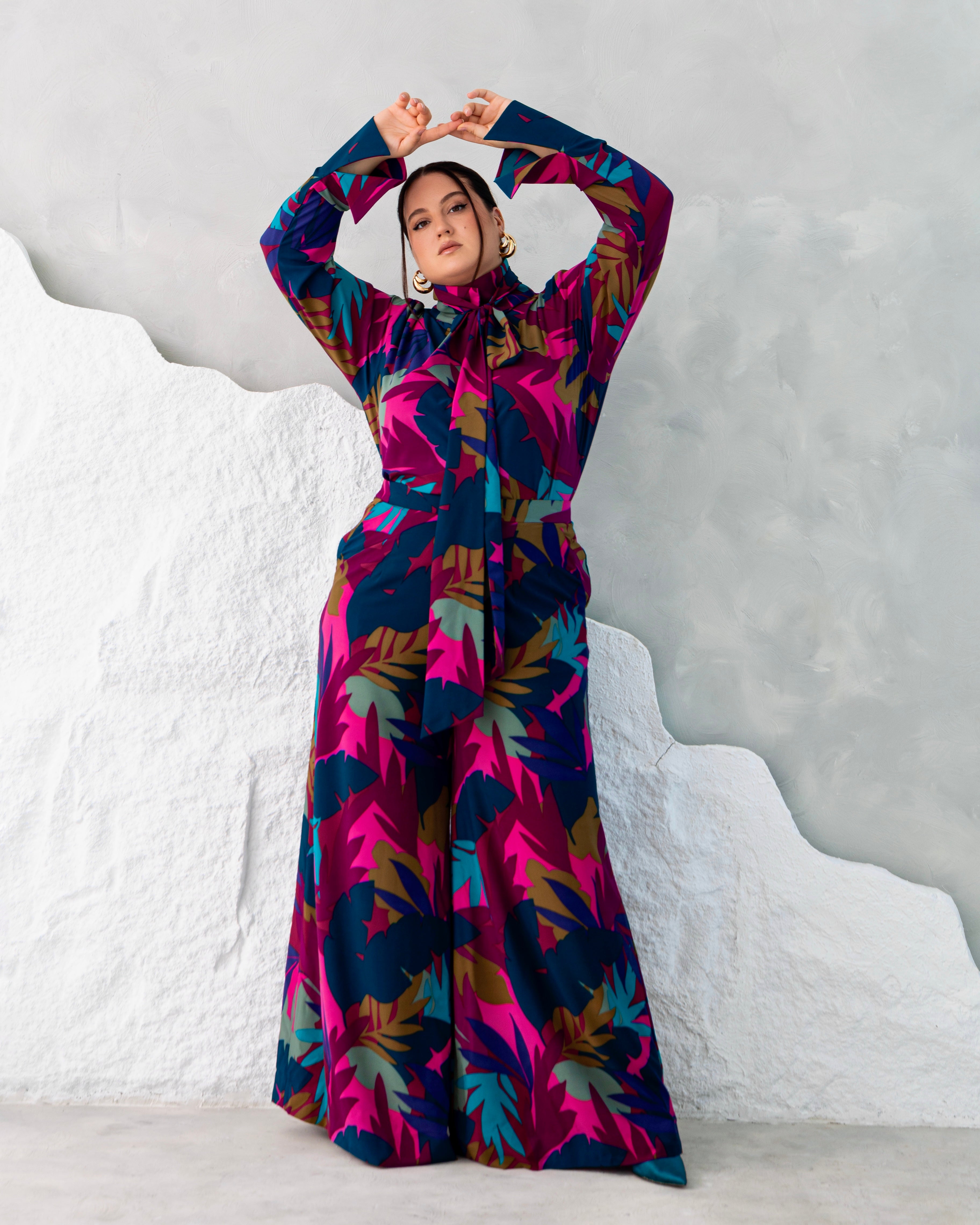 Model wearing Alona multicolor print set with high-neck tie detail and wide-leg pants, long sleeve silhouette.