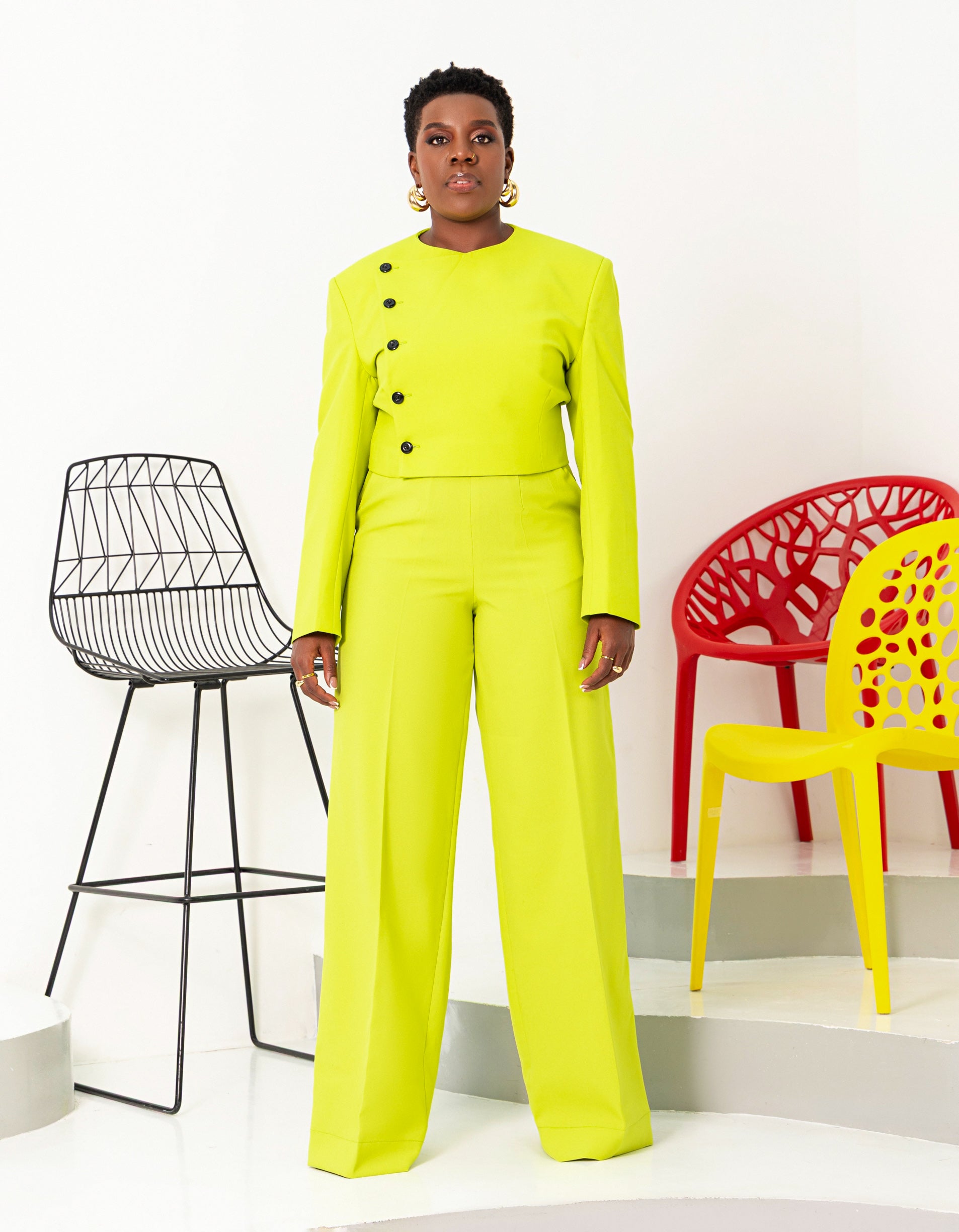 Fashion-forward model styled in a neon green cropped blazer with striking black buttons and matching trousers, exuding modern elegance and confidence.