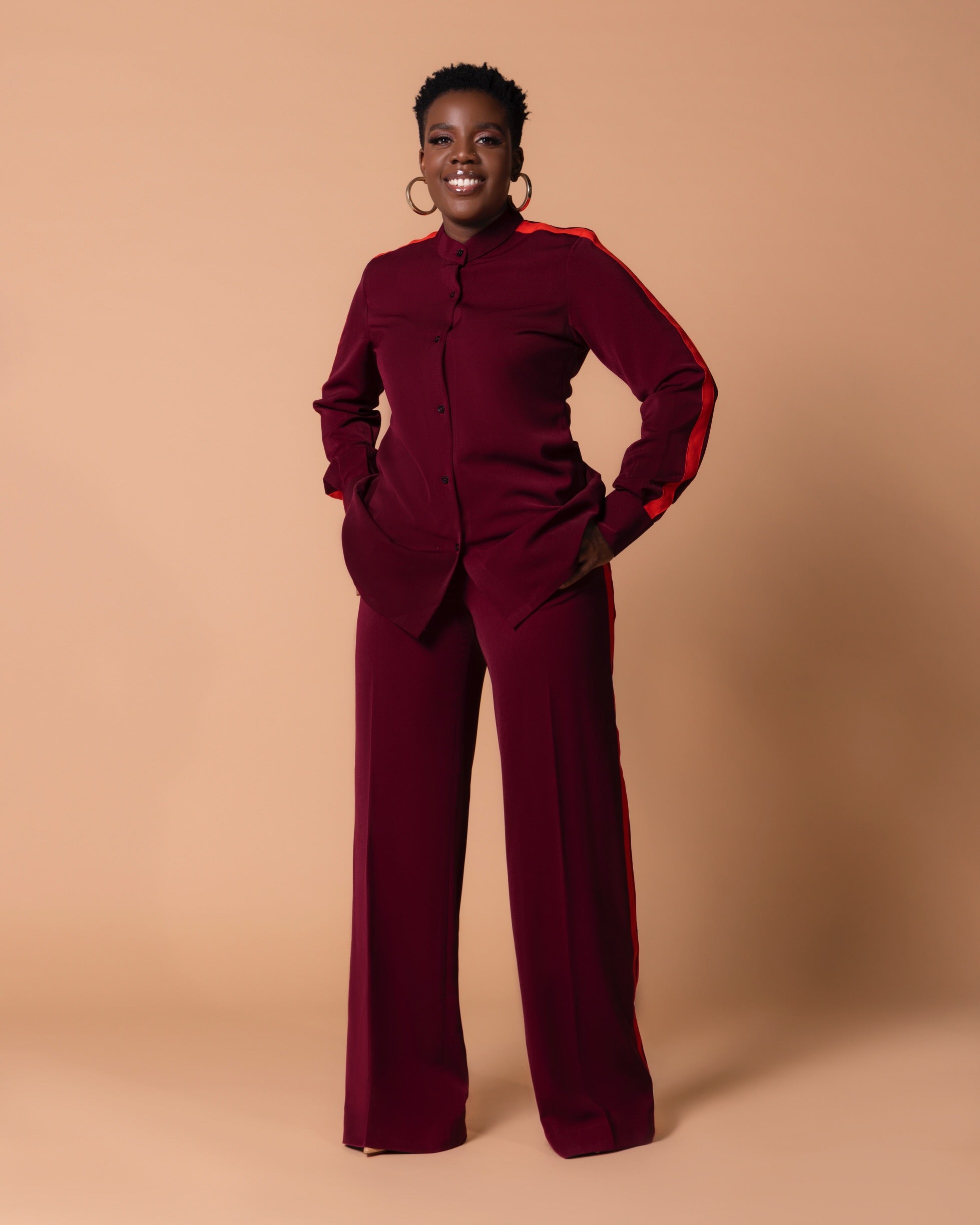 Front view of Maison Set: burgundy bishop-collar long-sleeve button shirt with orange shoulder-to-sleeve stripe, paired with high-waist straight-leg pants with double side stripes.
