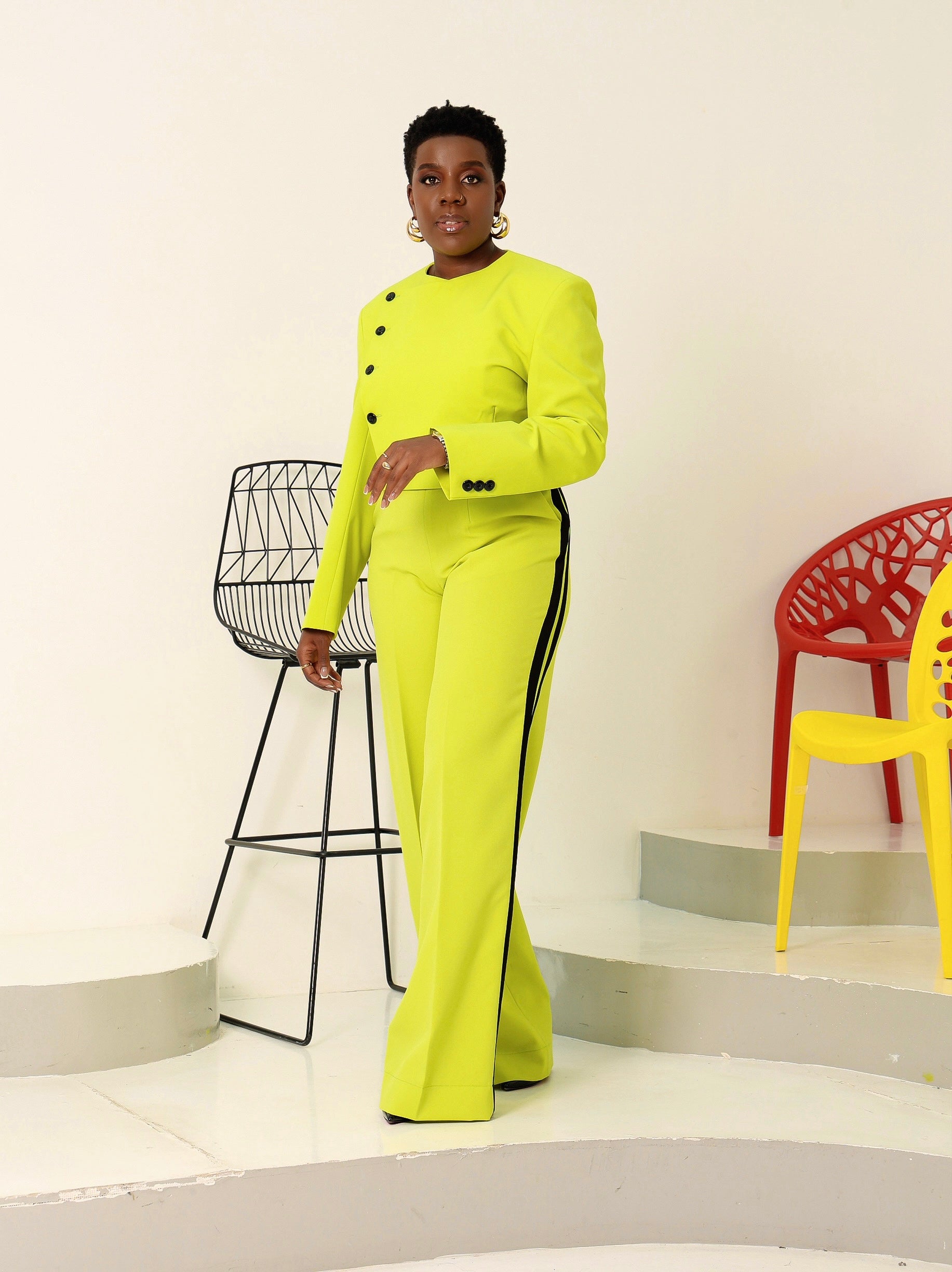 Fashion-forward model styled in a neon green cropped blazer with striking black buttons and matching trousers, exuding modern elegance and confidence.
