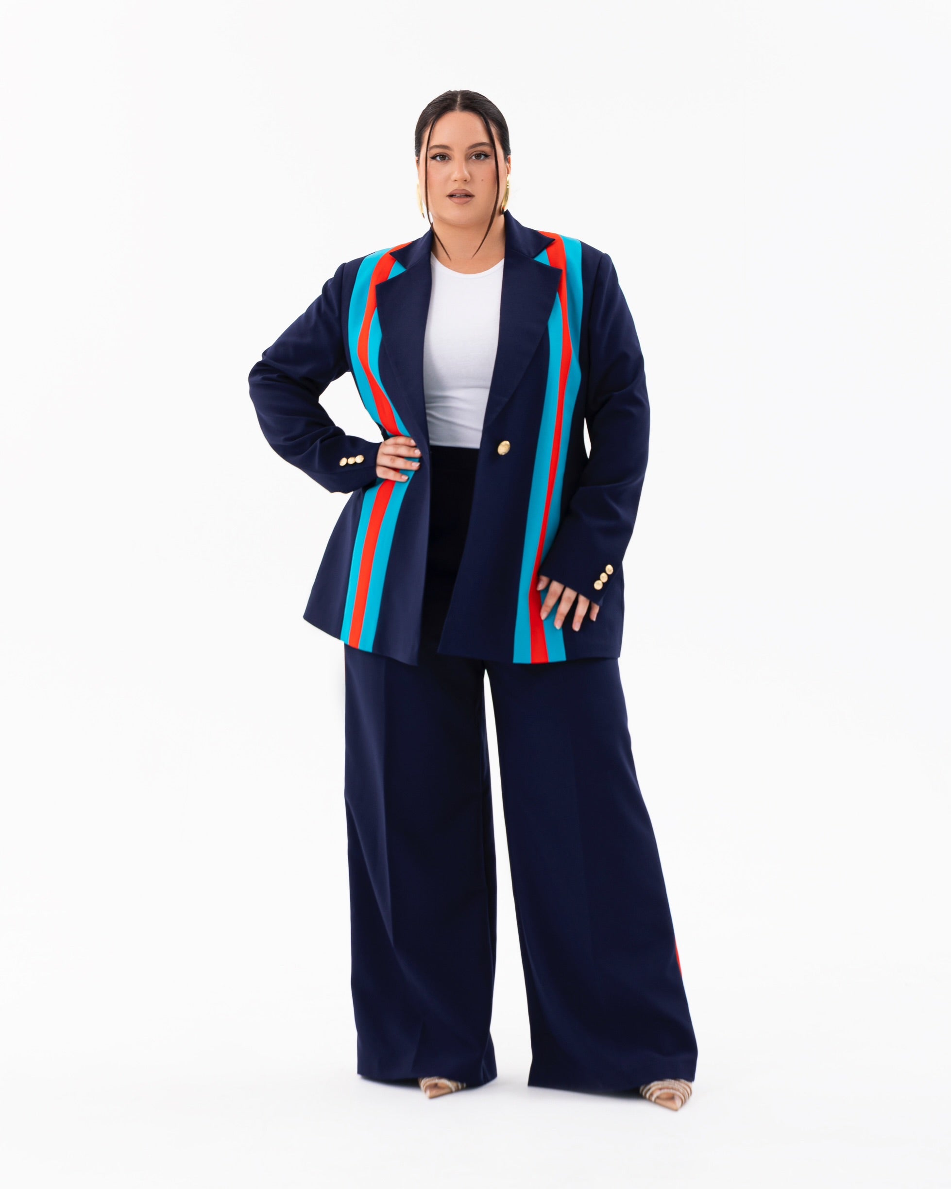 A plus-size European model wearing a navy blue suit set with teal and orange vertical stripe accents, consisting of tailored blazers, and straight pants, styled for bold, inclusive fashion.