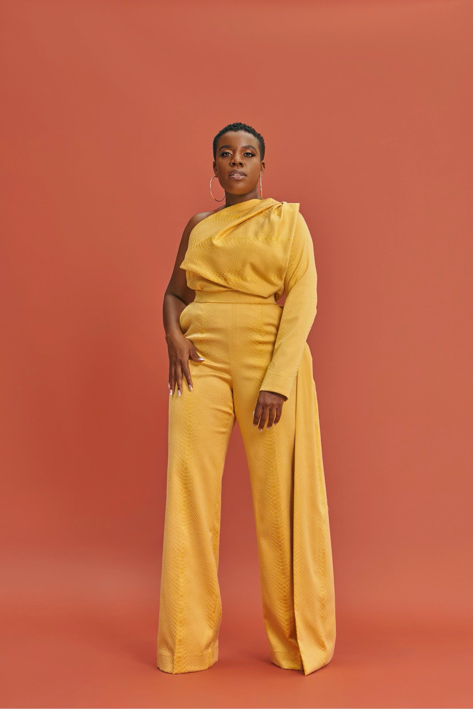 Co-ord set in goldish-yellow brocade – one-shoulder long sleeve top with bold bow detail, high-waist wide-leg pants with side flap