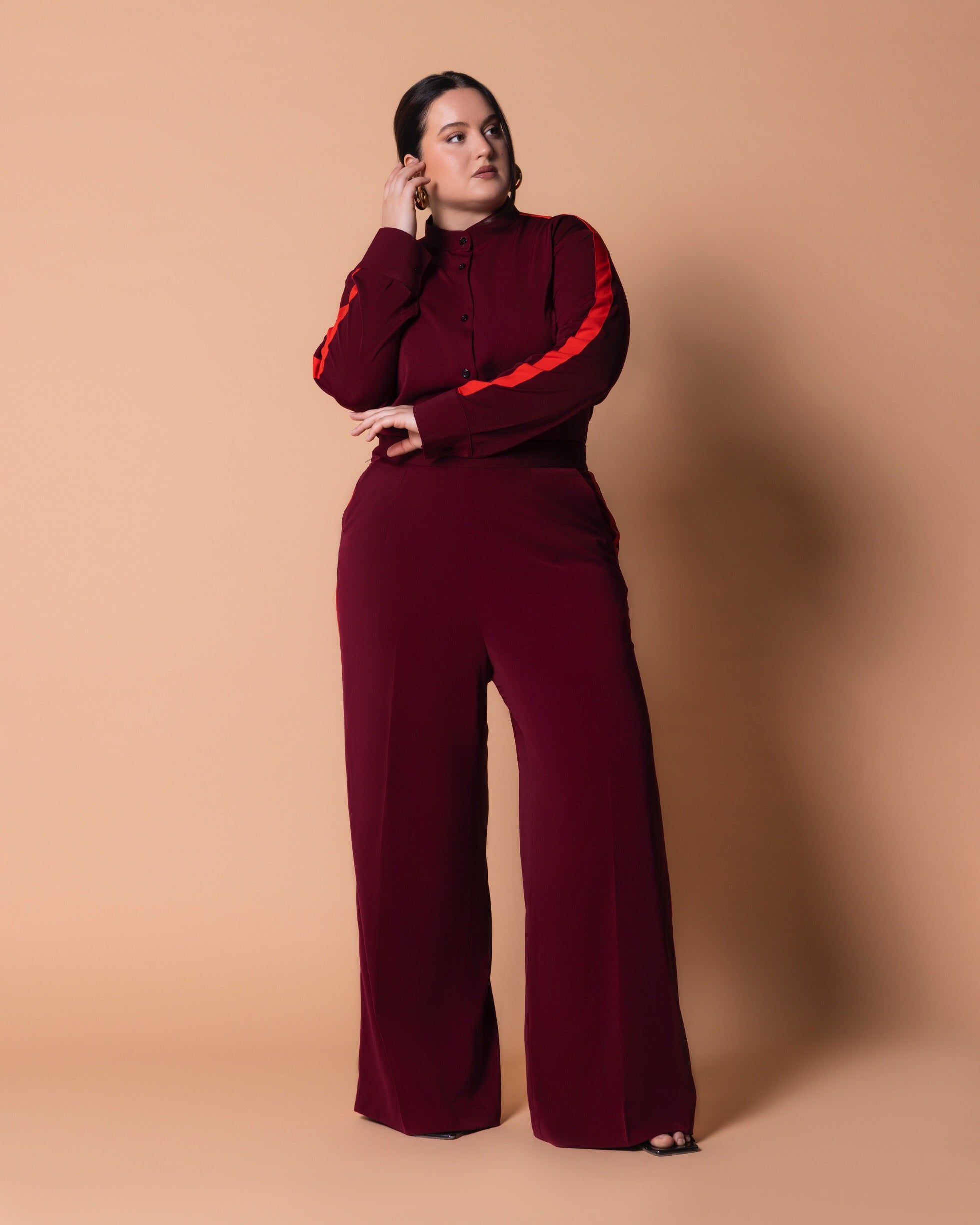 Front view of Maison Set: burgundy bishop-collar long-sleeve button shirt with orange shoulder-to-sleeve stripe, paired with high-waist straight-leg pants with double side stripes.