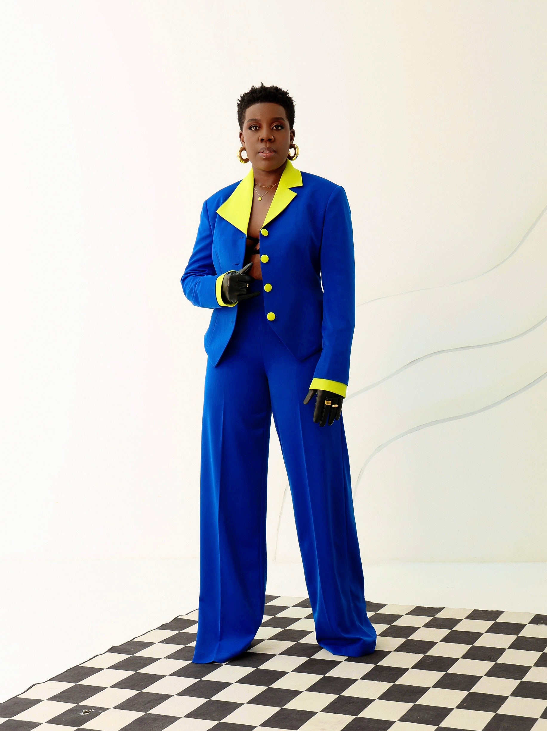 Contemporary royal blue pantsuit with neon details, worn by a model posing on a checkered floor.