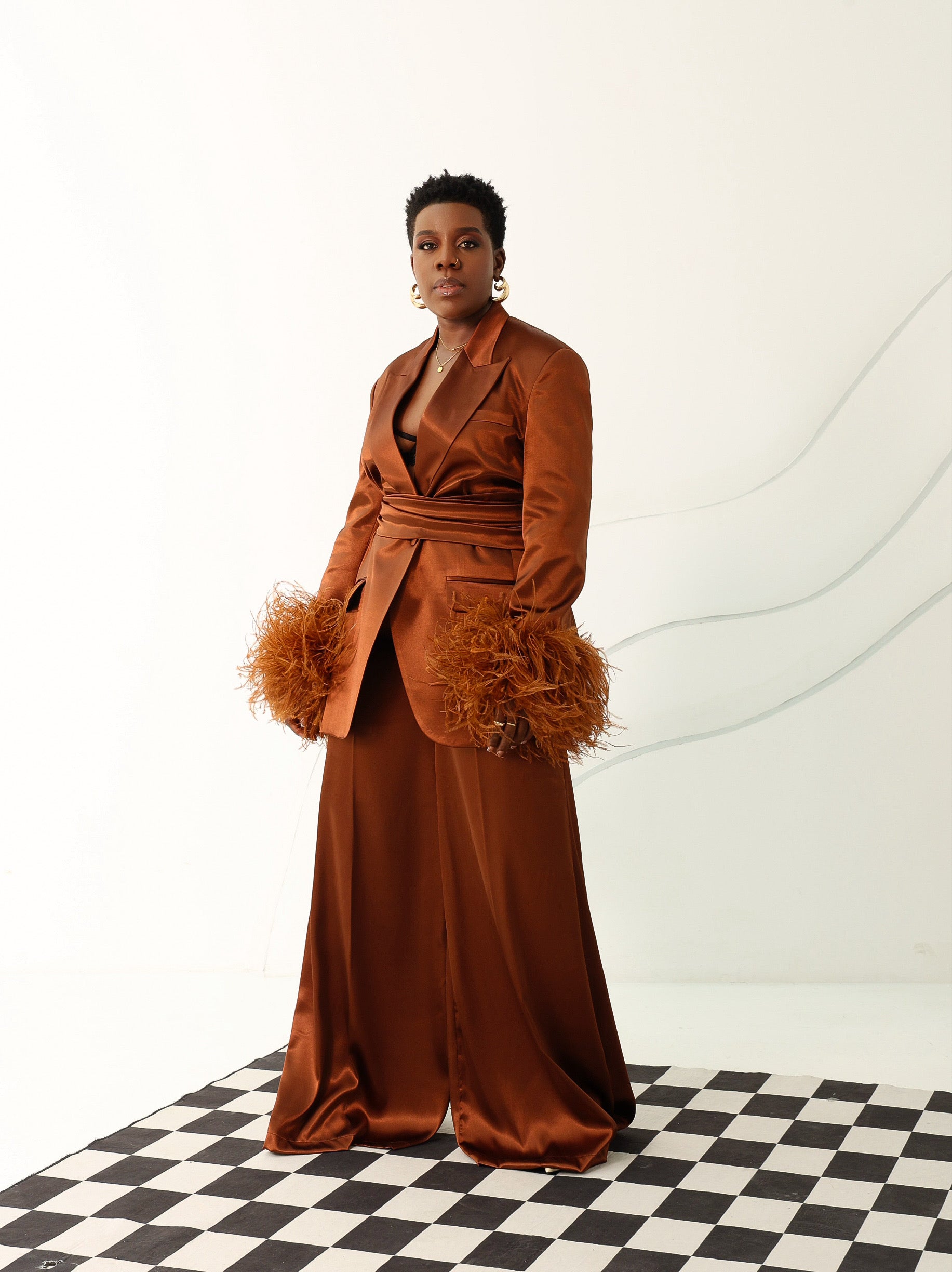 Model wearing Olarsgrace’s Taylor satin-silk suit set with feathered sleeves, belted blazer, and wide-leg pants in bronze.