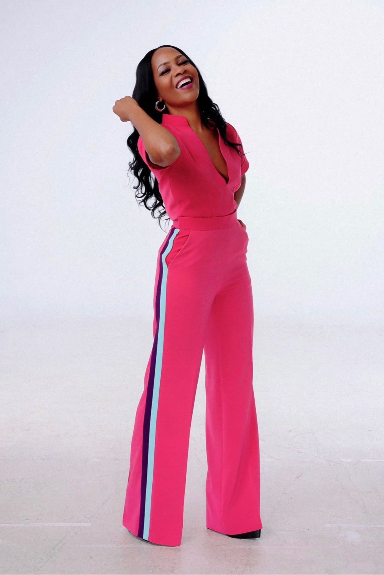 An elegant pink two-piece set featuring a deep V-neck top and wide-leg pants with contrast side stripes. Comfortable, luxe, and statement-ready. UK 6–24.