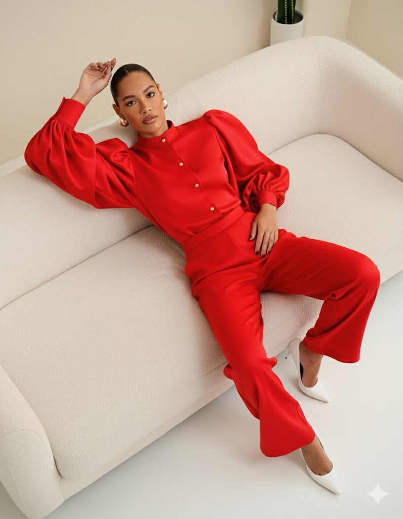 Model wearing red Shabir Set with bishop-collar button top, gold buttons and exaggerated balloon sleeves, styled with matching high-waist tailored pants and white heels.