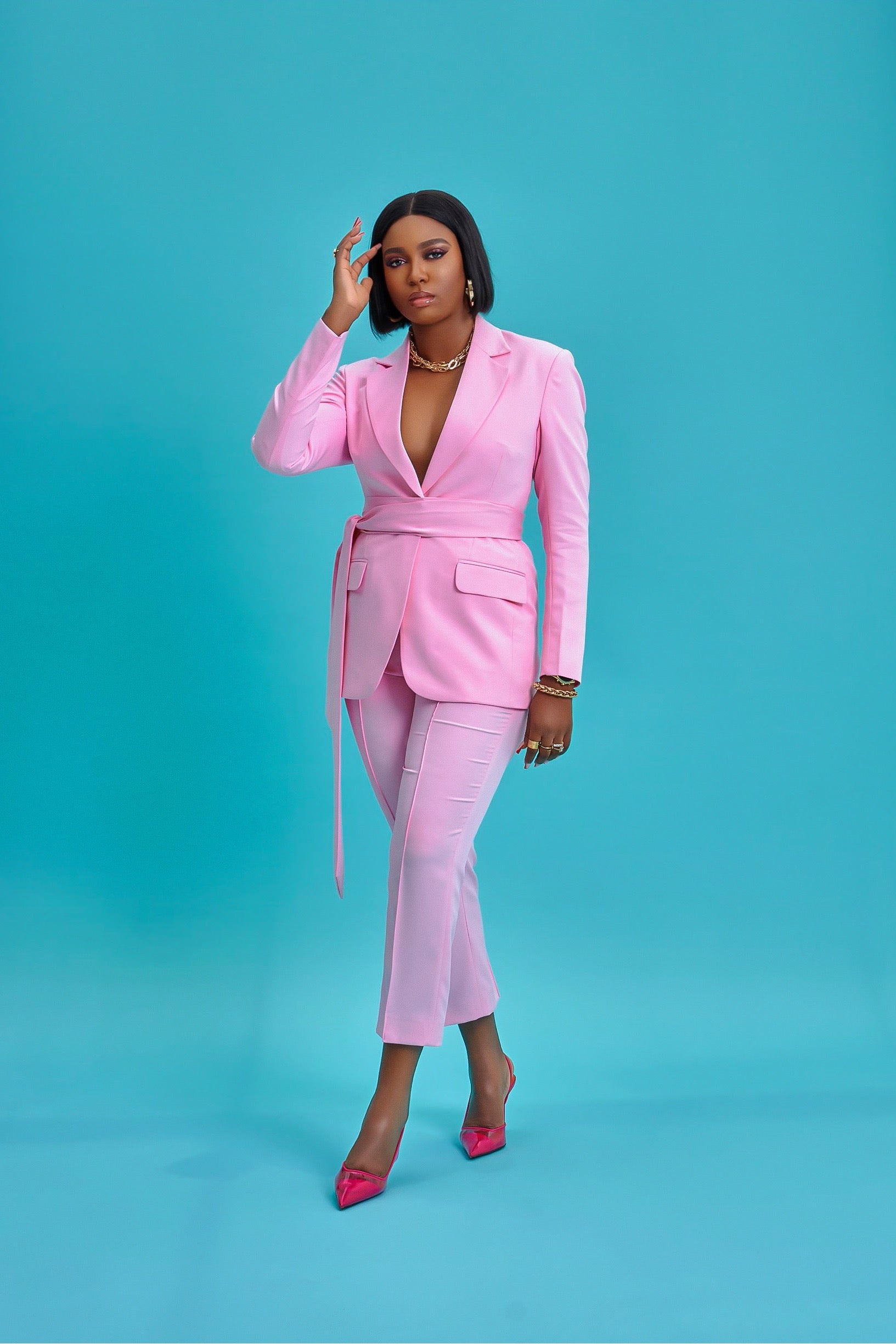 Model is wearing an elegant pink suit set with a high-waist cropped pants, and a belt that snatches and defines the waist effortlessly.