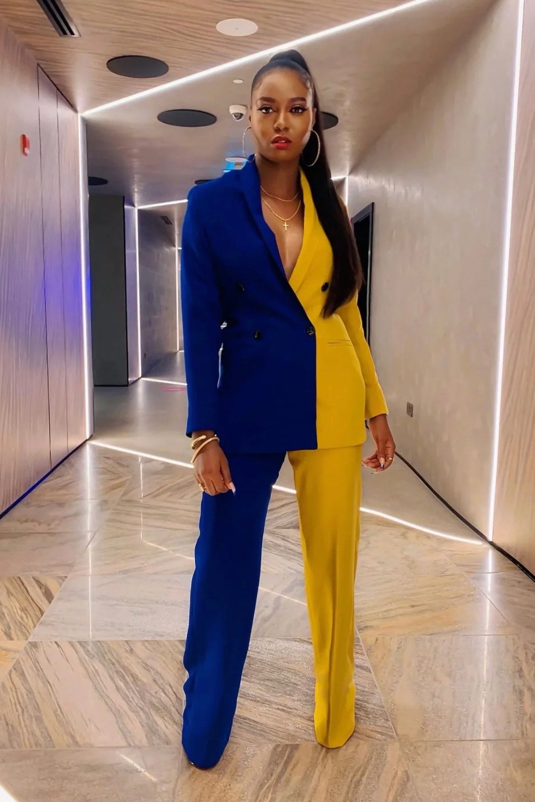 Model in color block blue and mustard yellow women’s suit set with tailored blazer and high-waist pants