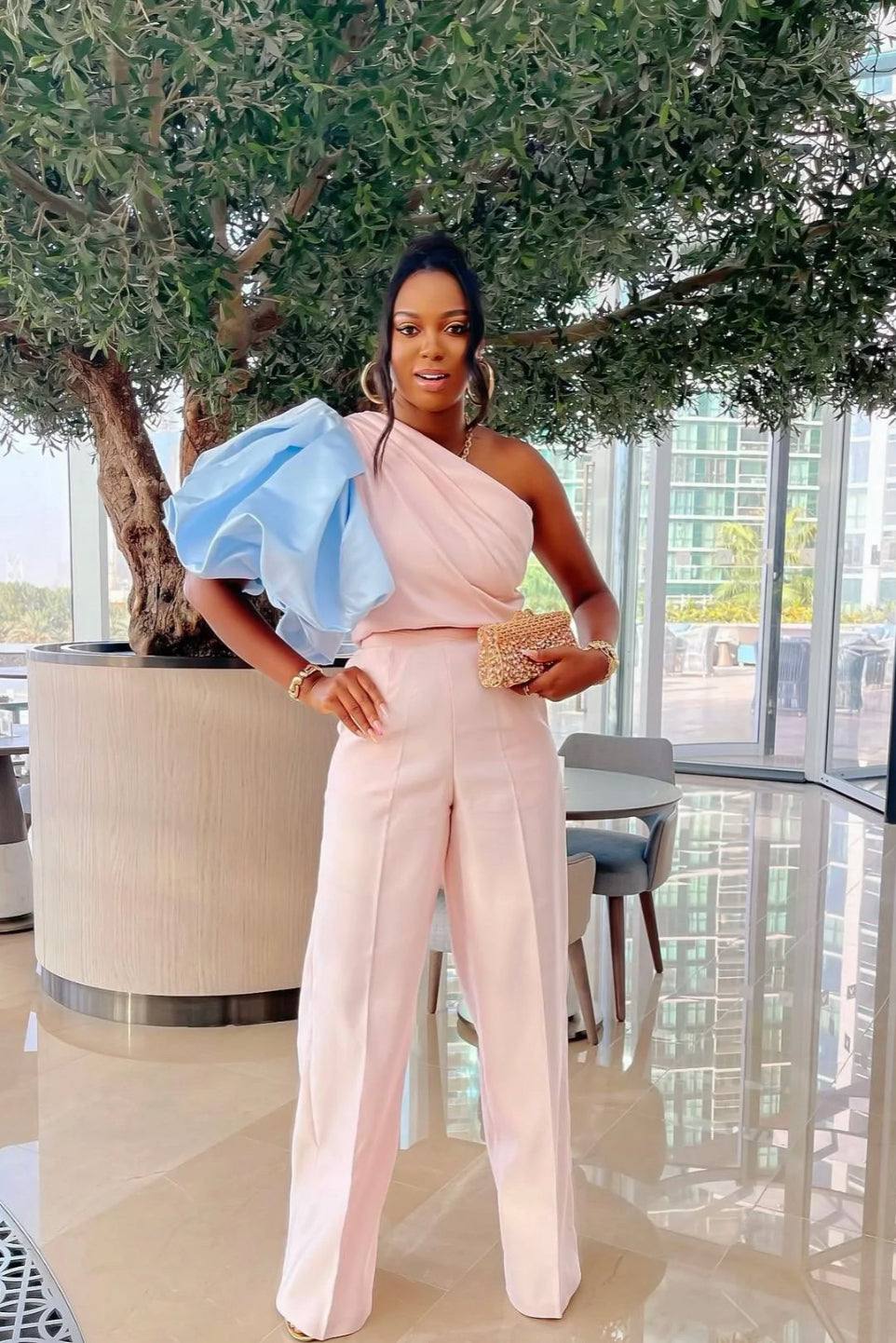 Model wearing Paris Set featuring blush pink one-shoulder top with sky blue balloon sleeve and matching high-waist wide-leg pants.