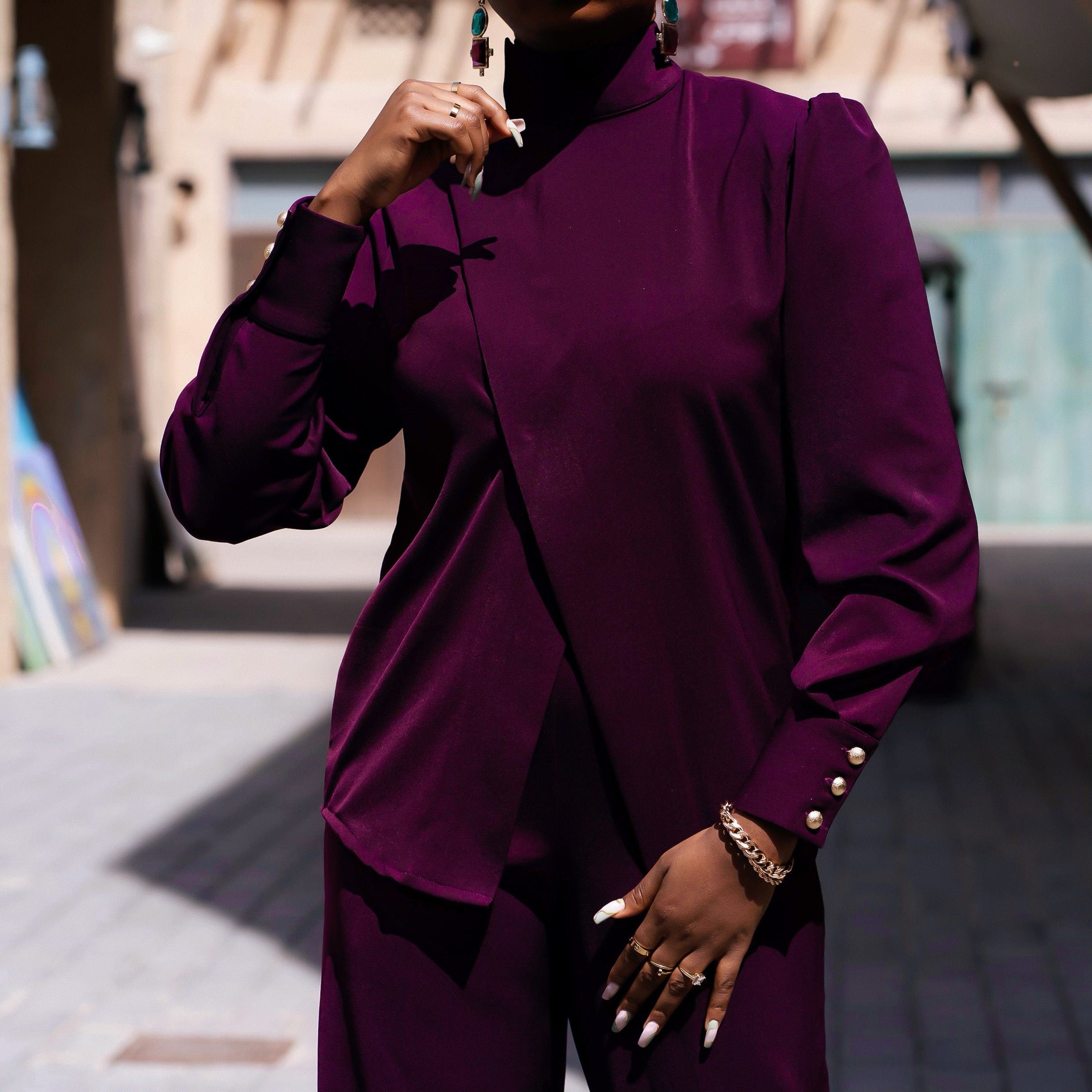 Detail shot of the Bako Set showing the asymmetric front panel on the purple turtleneck top and matching high-waist straight-leg pants in premium crepe.