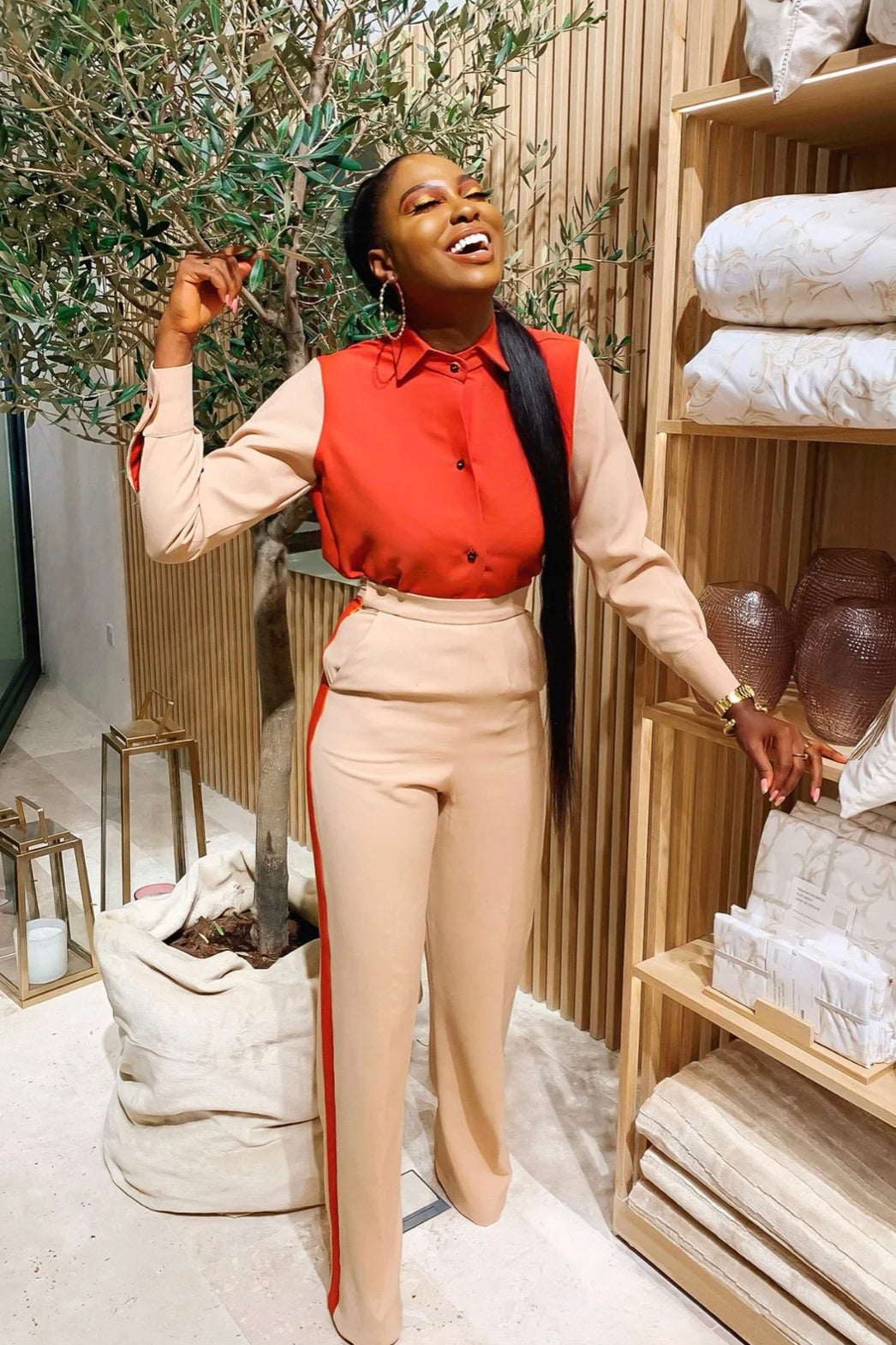 Model wearing Tayo Set nude and orange colourblock long-sleeve button shirt from Olarsgrace, paired with a matching high-waist straight-leg pants featuring double orange side stripes.